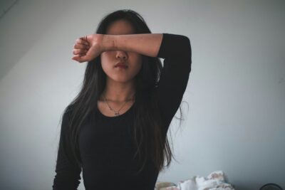 this is the image of a woman covering her eyes with her arm because she is stressed and experiencing symptoms of depression and anxiety