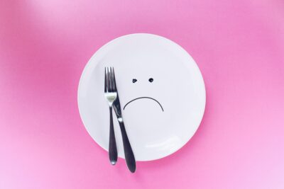 image of a white dinner plate with a sad face drawn on it, representing the Standard American Diet, or the SAD diet