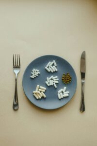 this is the image of a blue plate with vitamin supplements placed on it with a fork its left-hand side and a knife on its right-hand side